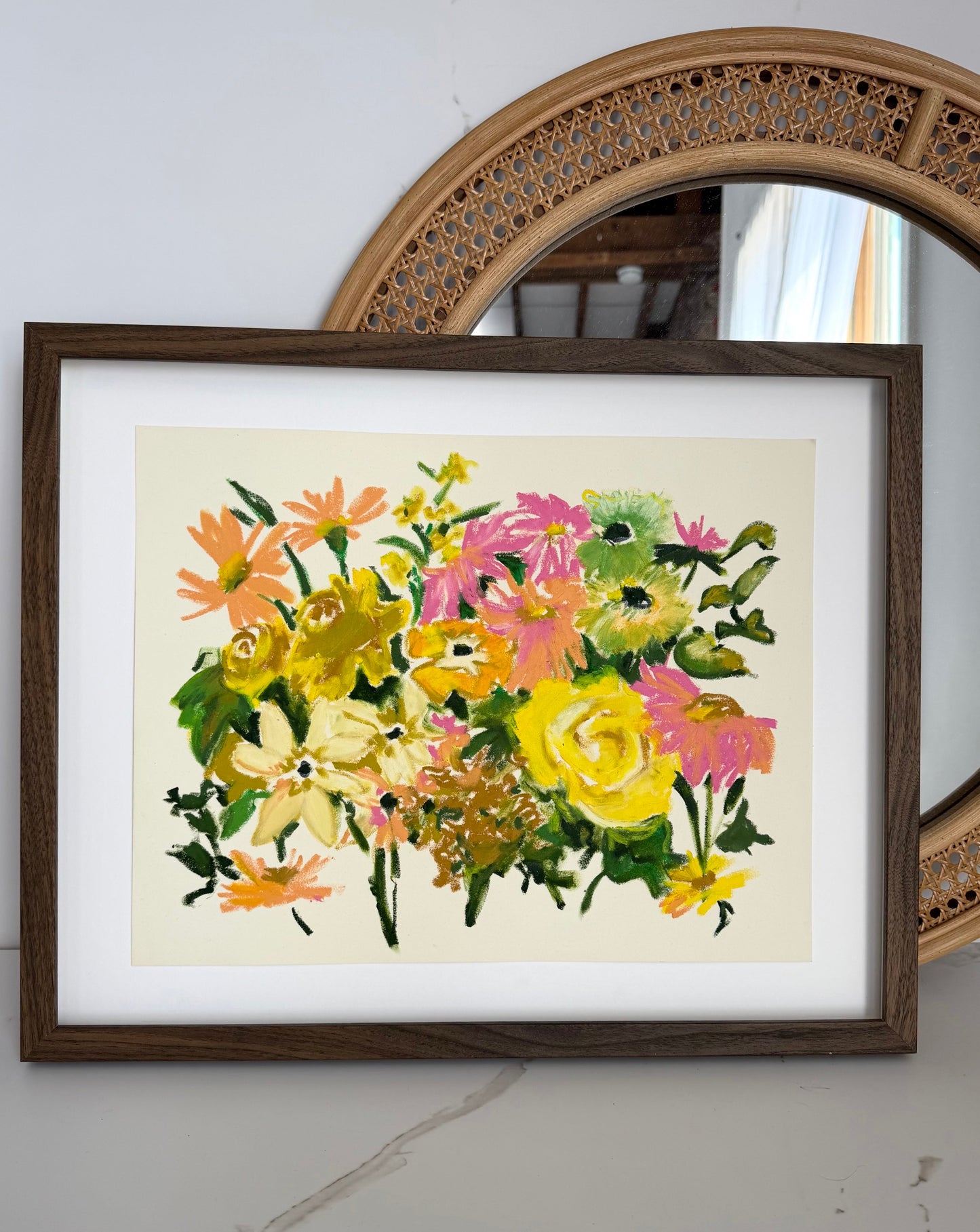 Framed floral painting on a wall next to a mirror